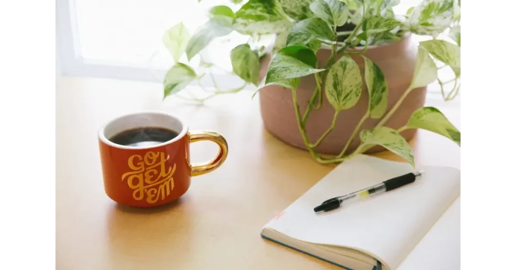 Coffee on table with notebook and plant