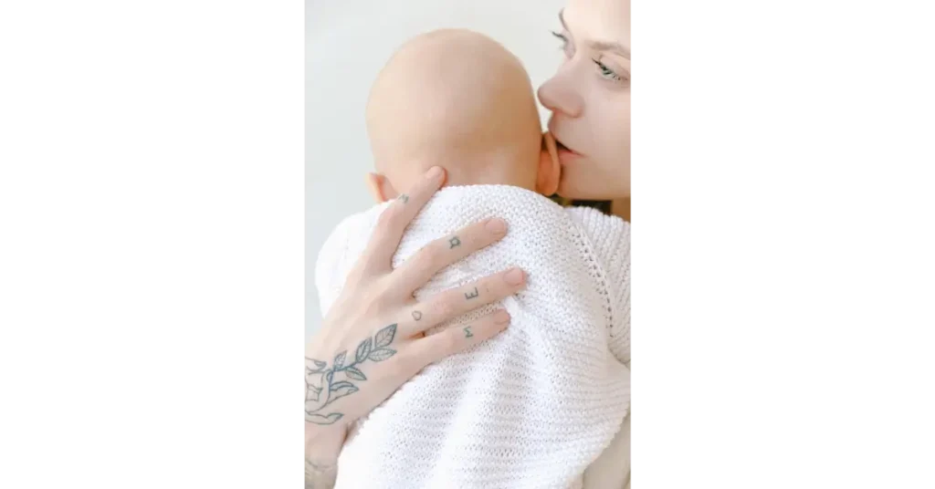 Woman holding a baby with a hand full of tattoos