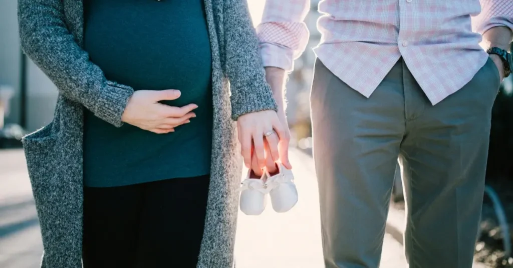 Two parents holding baby shoes together