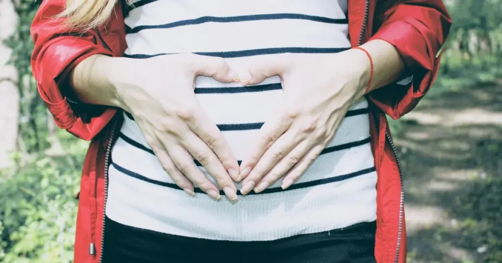 Hands forming hearth over pregant baby belly
